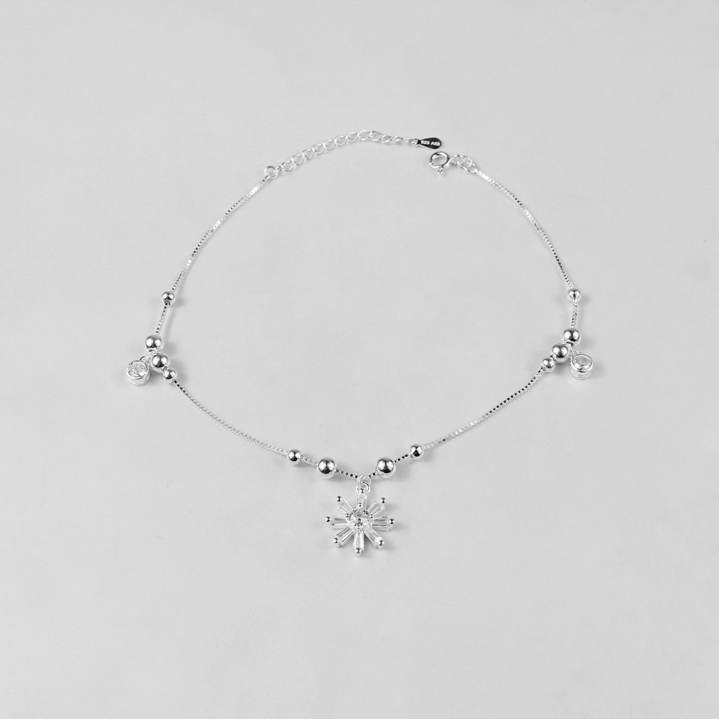 The 'Floral Charm' anklet, crafted from 925 sterling silver, featuring a graceful chain adorned with intricate floral-inspired charms for a touch of elegance.