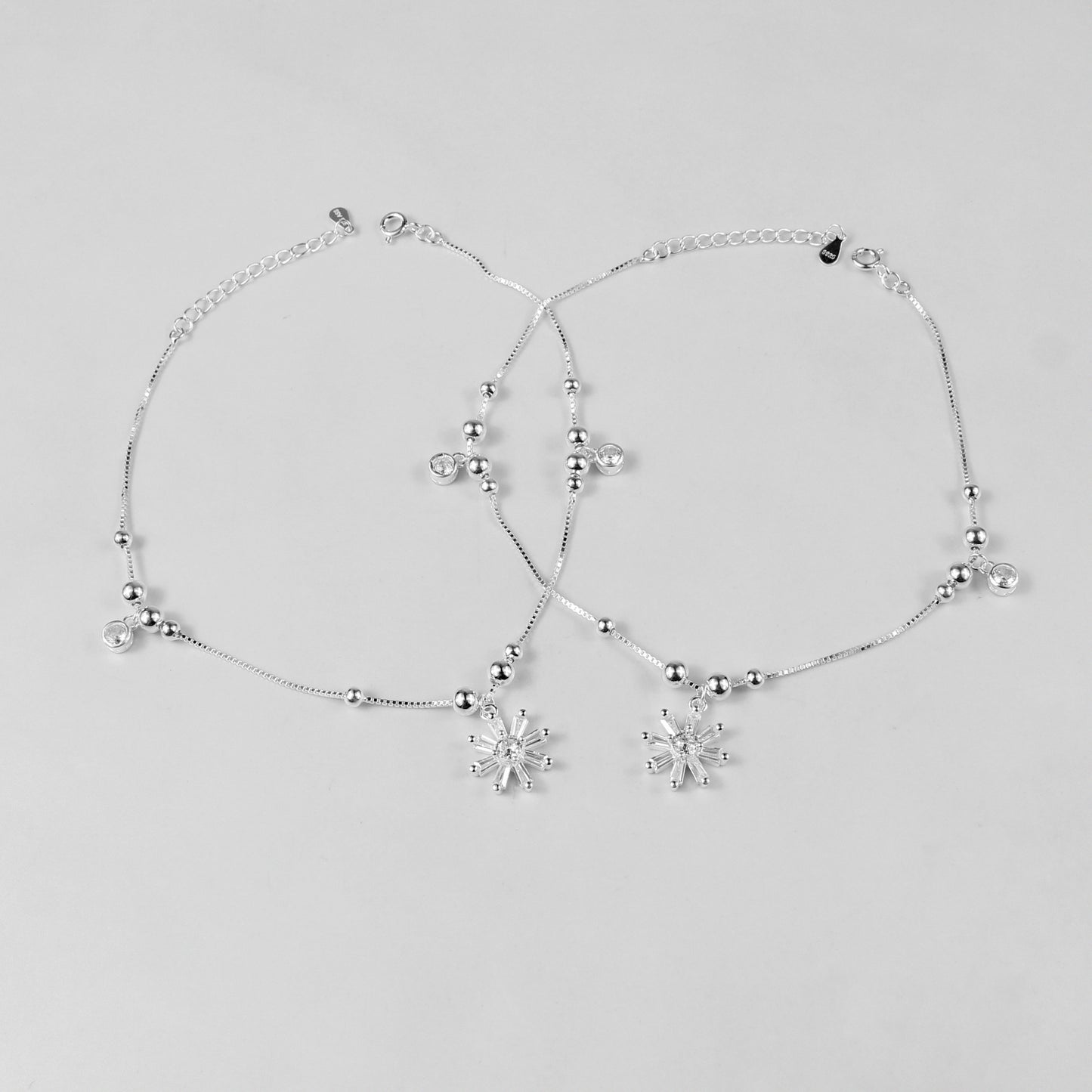 The 'Floral Charm' anklet, crafted from 925 sterling silver, featuring a graceful chain adorned with intricate floral-inspired charms for a touch of elegance.