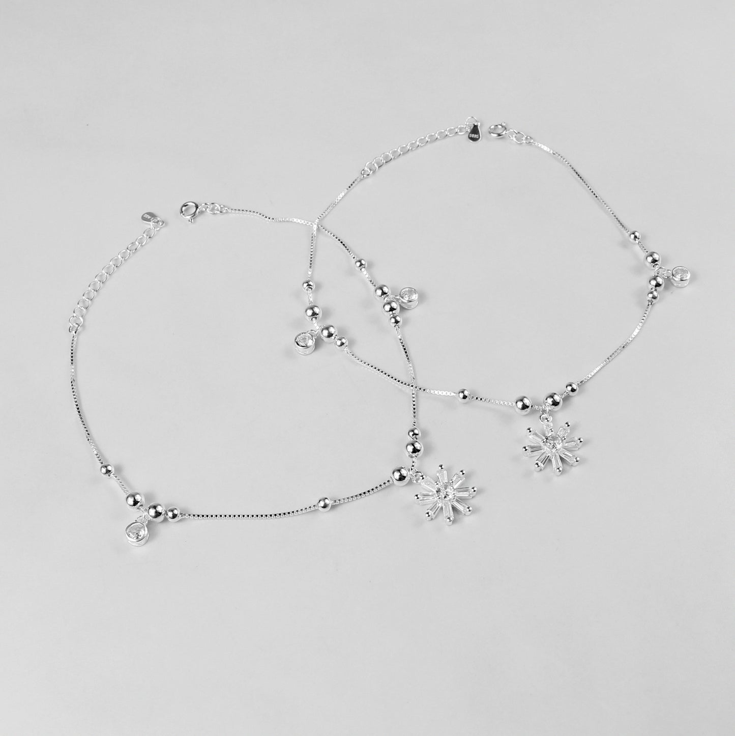 The 'Floral Charm' anklet, crafted from 925 sterling silver, featuring a graceful chain adorned with intricate floral-inspired charms for a touch of elegance.