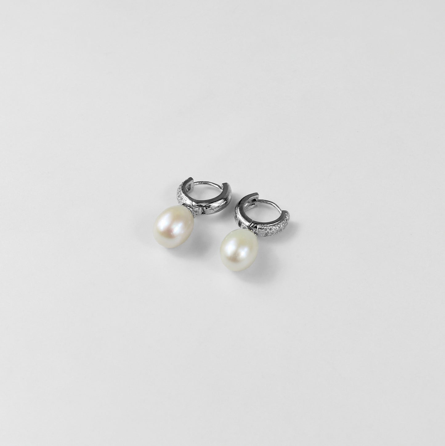 A pair of timeless 925 sterling silver ear studs featuring luminous pearls at their center. The design exudes elegance and grace, making these studs a classic accessory for any occasion, from casual outings to formal events.