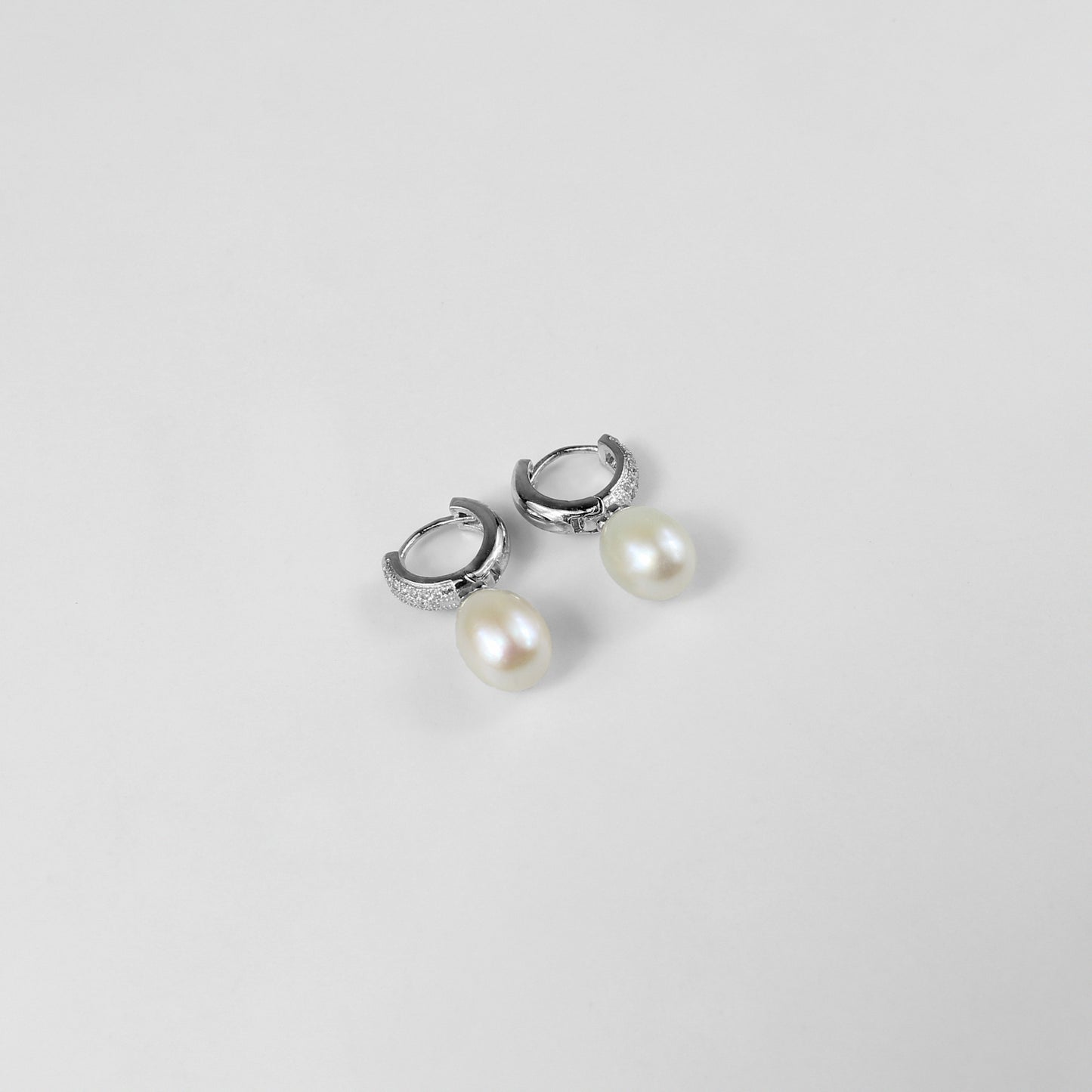 A pair of timeless 925 sterling silver ear studs featuring luminous pearls at their center. The design exudes elegance and grace, making these studs a classic accessory for any occasion, from casual outings to formal events.