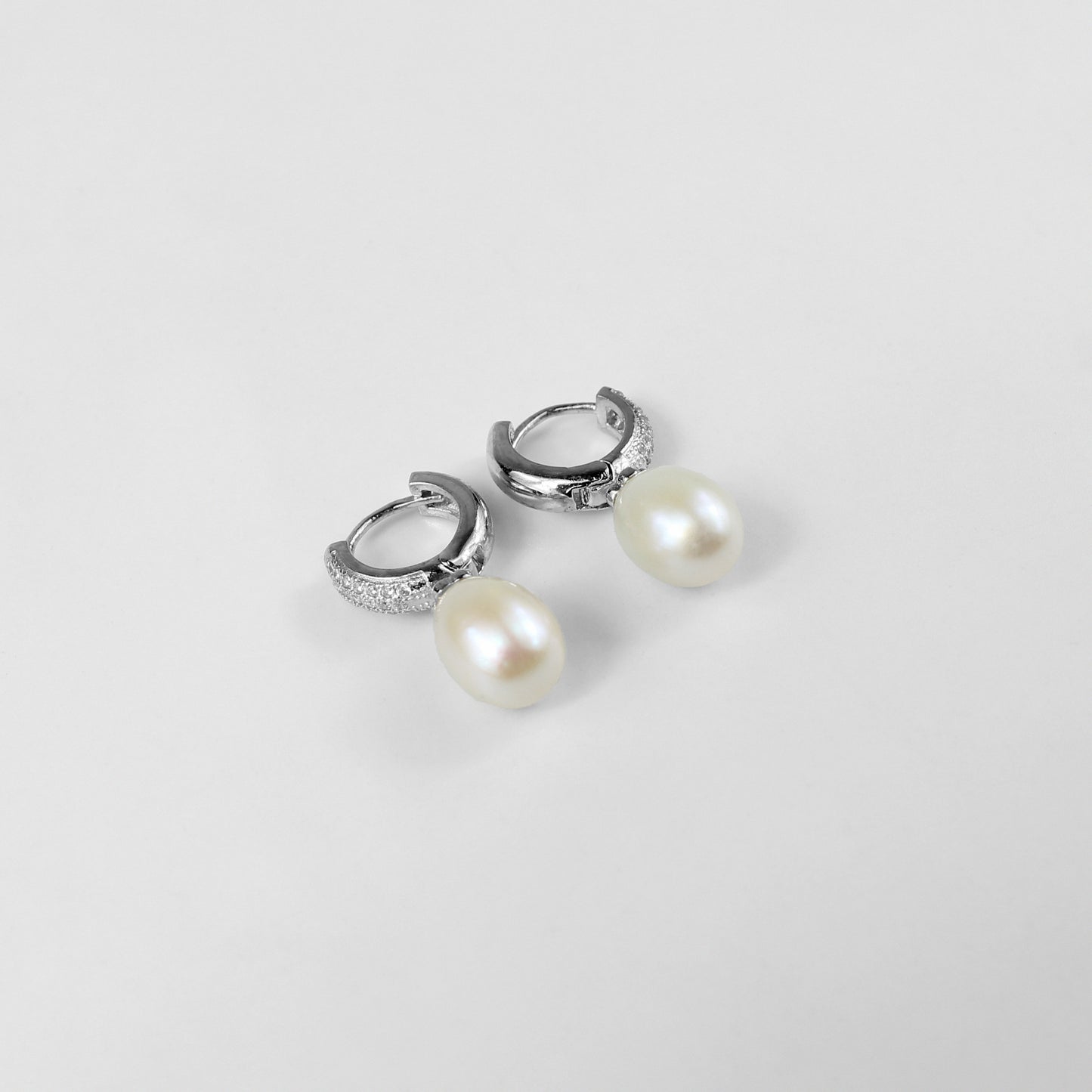 A pair of timeless 925 sterling silver ear studs featuring luminous pearls at their center. The design exudes elegance and grace, making these studs a classic accessory for any occasion, from casual outings to formal events.