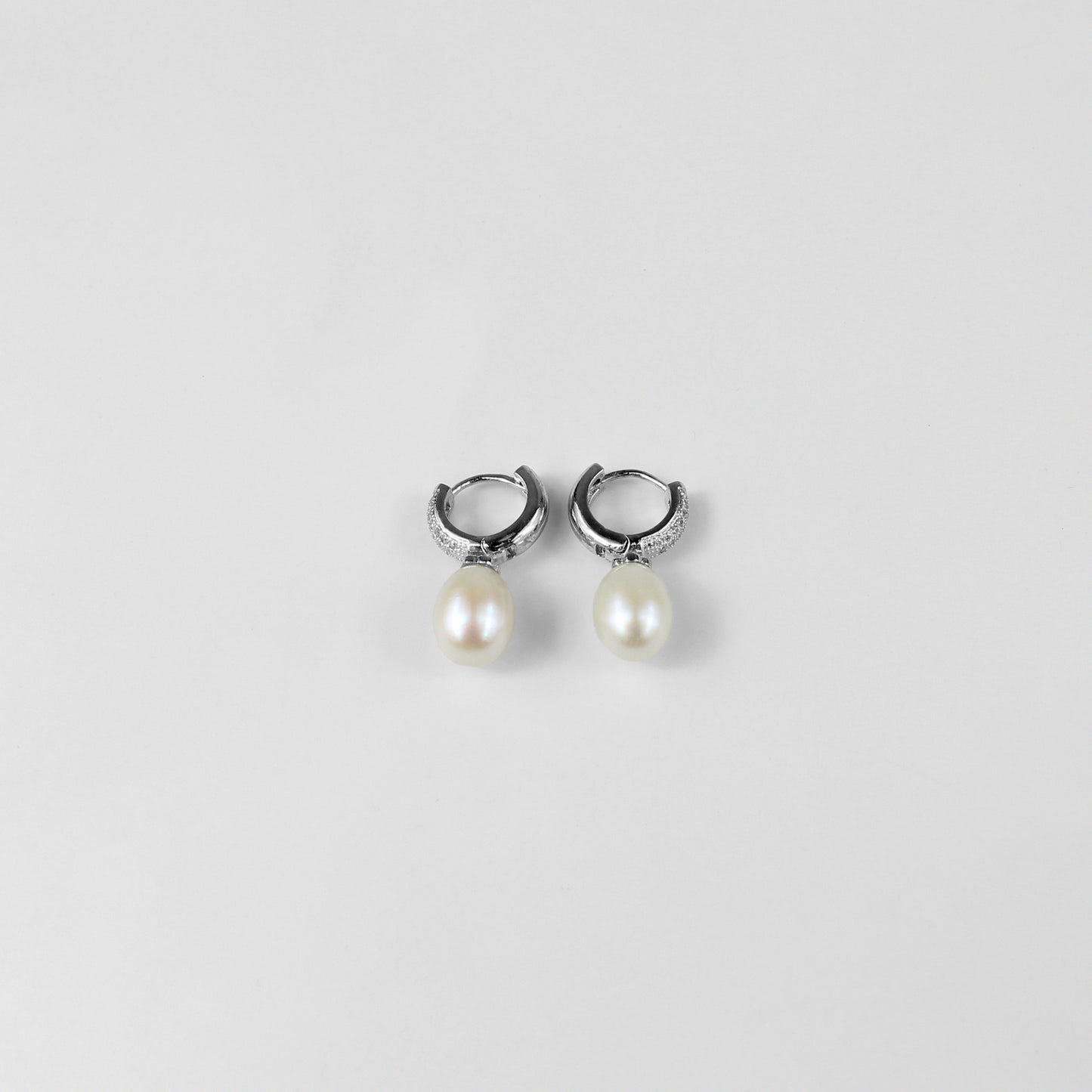 A pair of timeless 925 sterling silver ear studs featuring luminous pearls at their center. The design exudes elegance and grace, making these studs a classic accessory for any occasion, from casual outings to formal events.