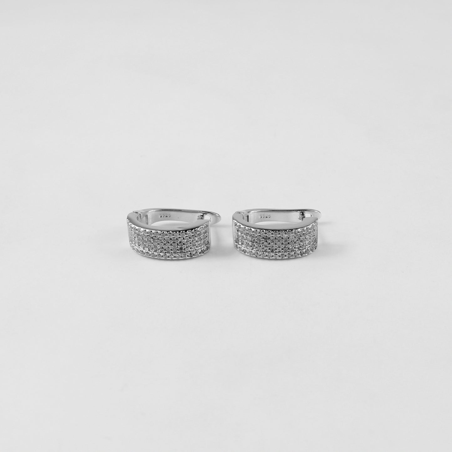 925 sterling silver ear studs titled 'Radiant Glow,' with luminous crystals creating an eye-catching radiance, displayed on a sleek marble surface.