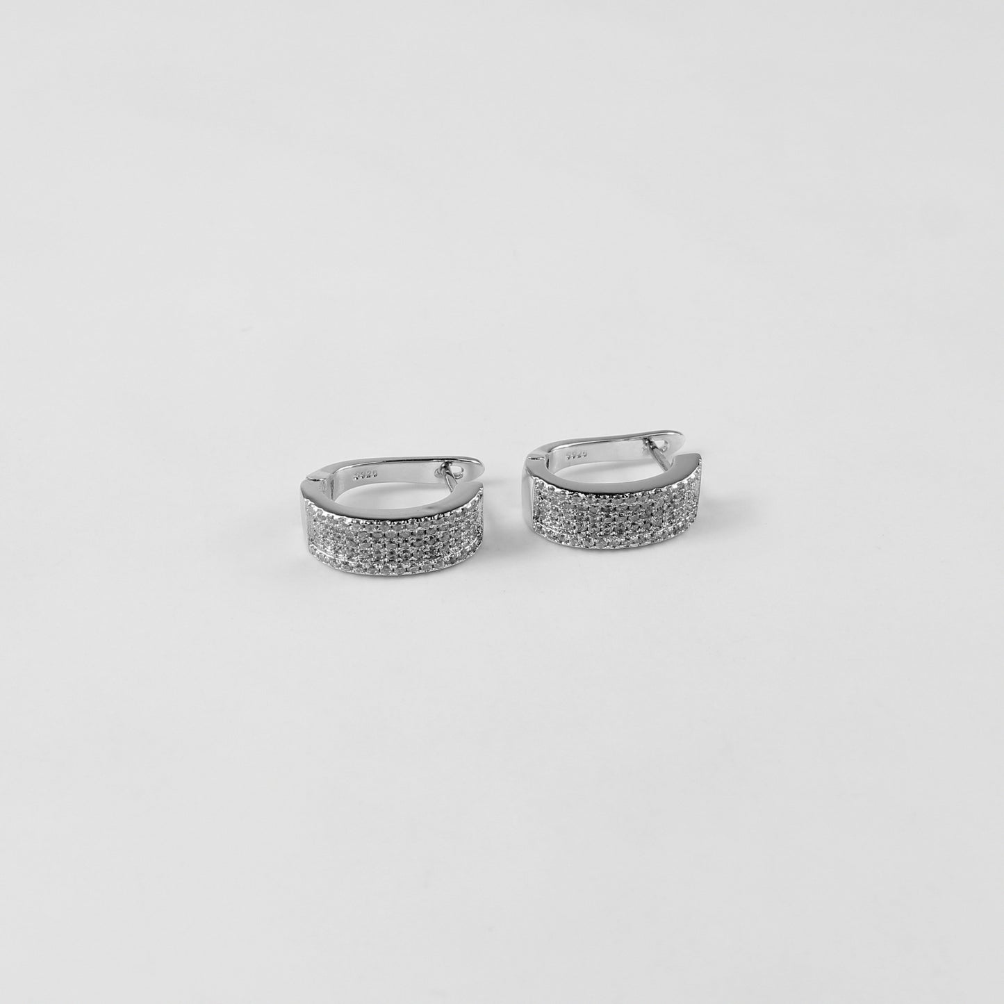 925 sterling silver ear studs titled 'Radiant Glow,' with luminous crystals creating an eye-catching radiance, displayed on a sleek marble surface.