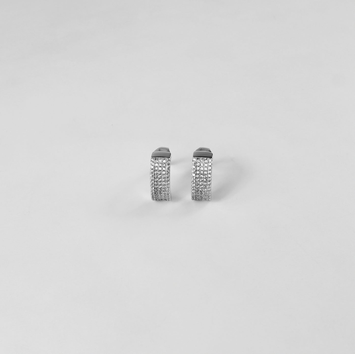 925 sterling silver ear studs titled 'Radiant Glow,' with luminous crystals creating an eye-catching radiance, displayed on a sleek marble surface.
