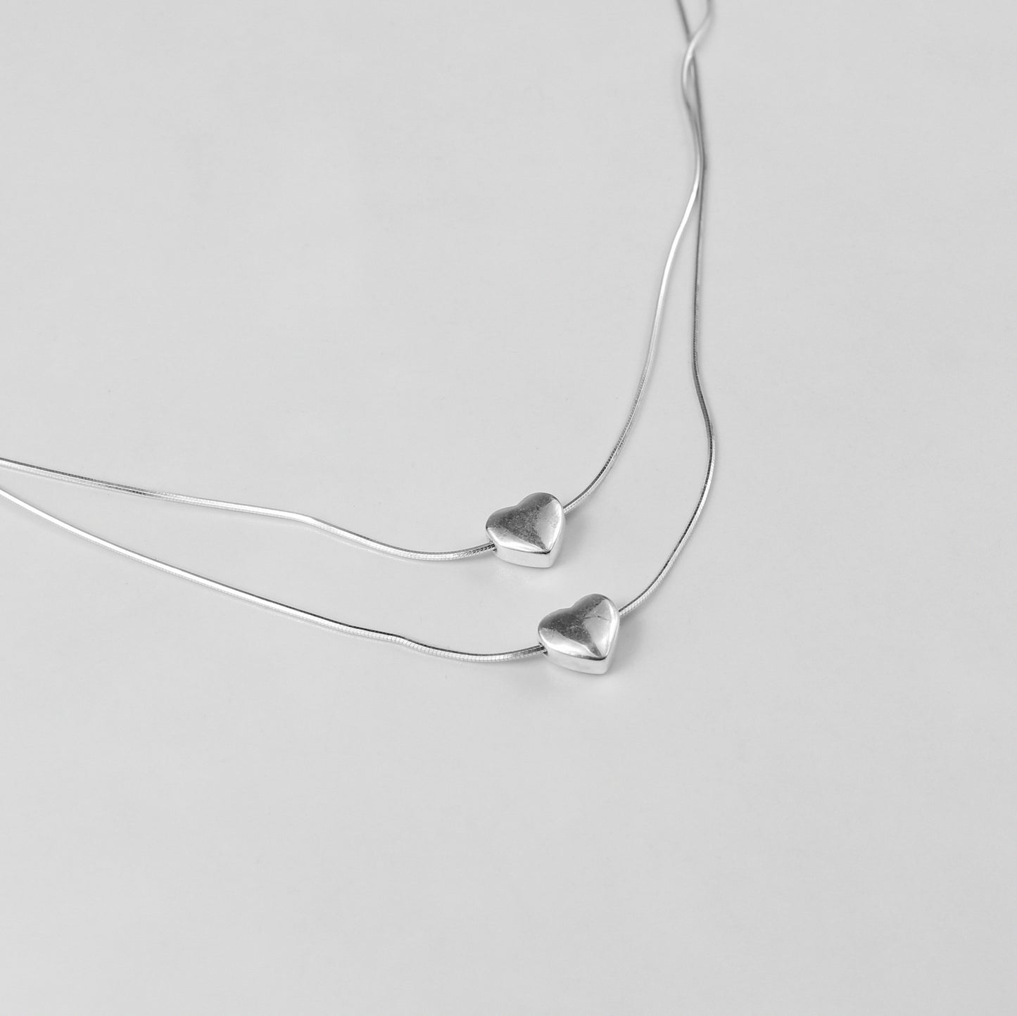 An exquisite necklace named 'Eternal Heartstrings,' crafted from 925 sterling silver. Its design features intertwining heart motifs, symbolizing everlasting love and connection with a refined elegance.