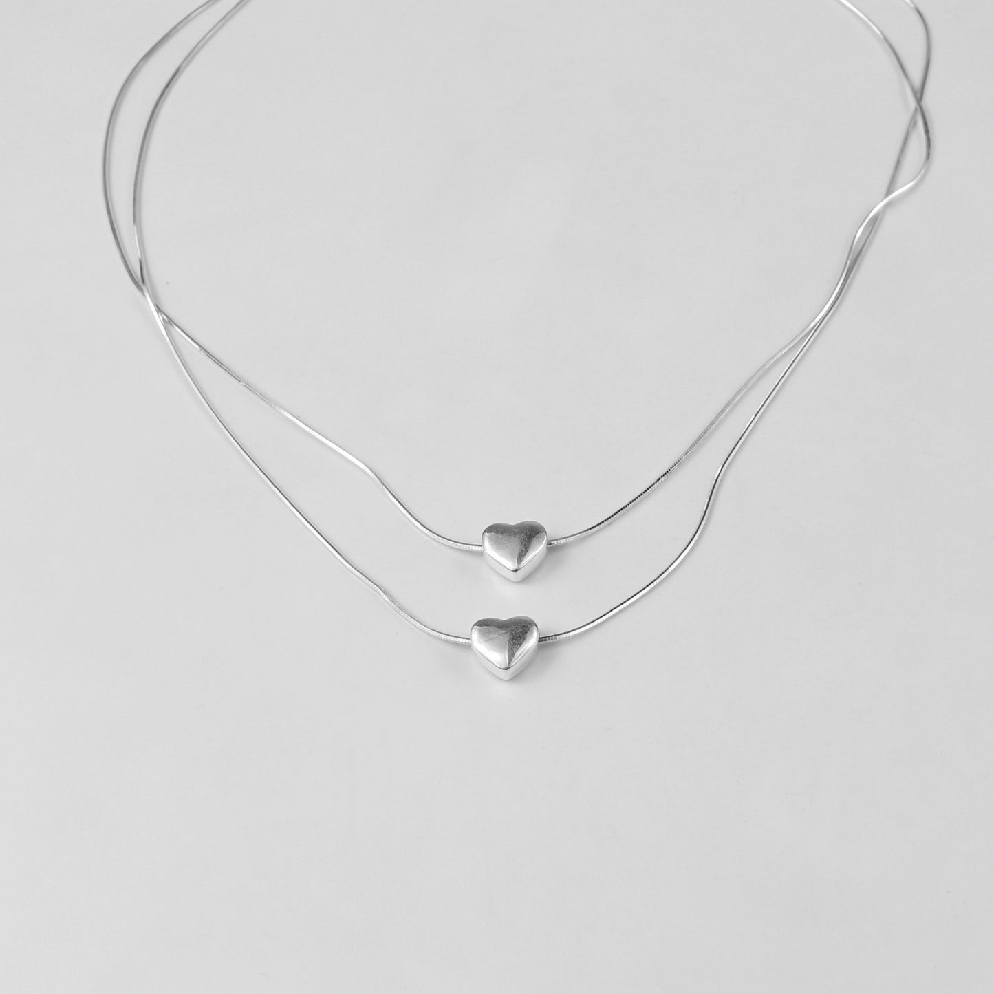 An exquisite necklace named 'Eternal Heartstrings,' crafted from 925 sterling silver. Its design features intertwining heart motifs, symbolizing everlasting love and connection with a refined elegance.