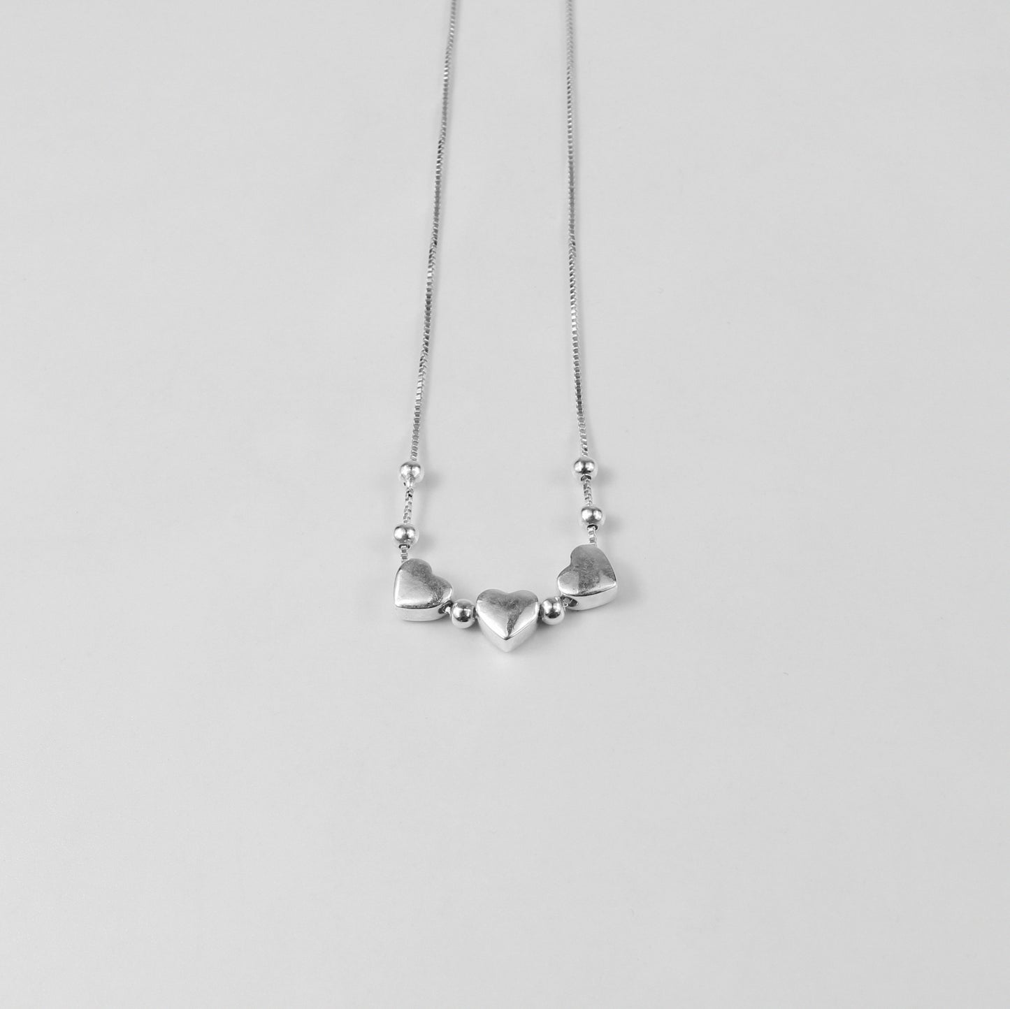 A charming necklace named 'Heartfelt Trio,' crafted from 925 sterling silver. Its design features three interlinked hearts, symbolizing love, connection, and unity with a timeless elegance.