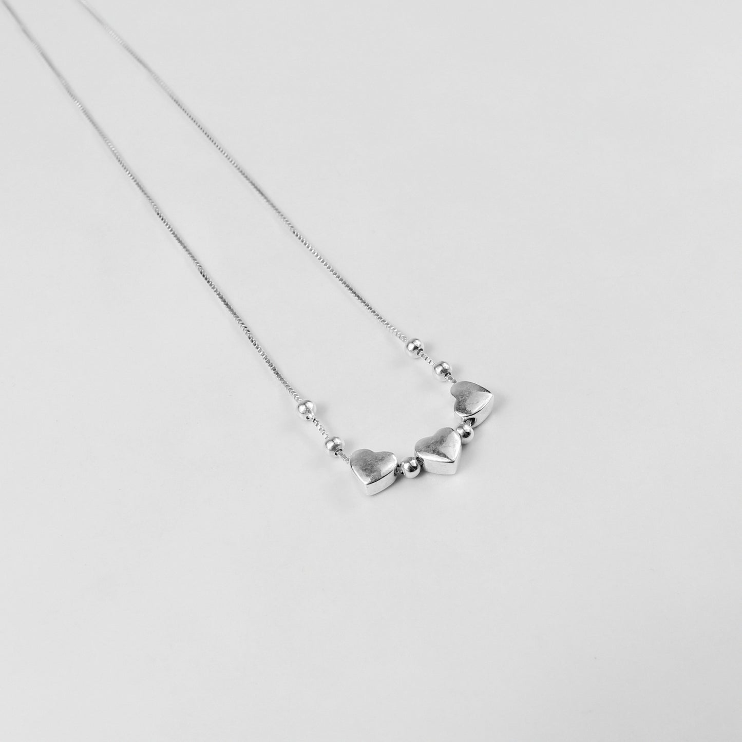 A charming necklace named 'Heartfelt Trio,' crafted from 925 sterling silver. Its design features three interlinked hearts, symbolizing love, connection, and unity with a timeless elegance.