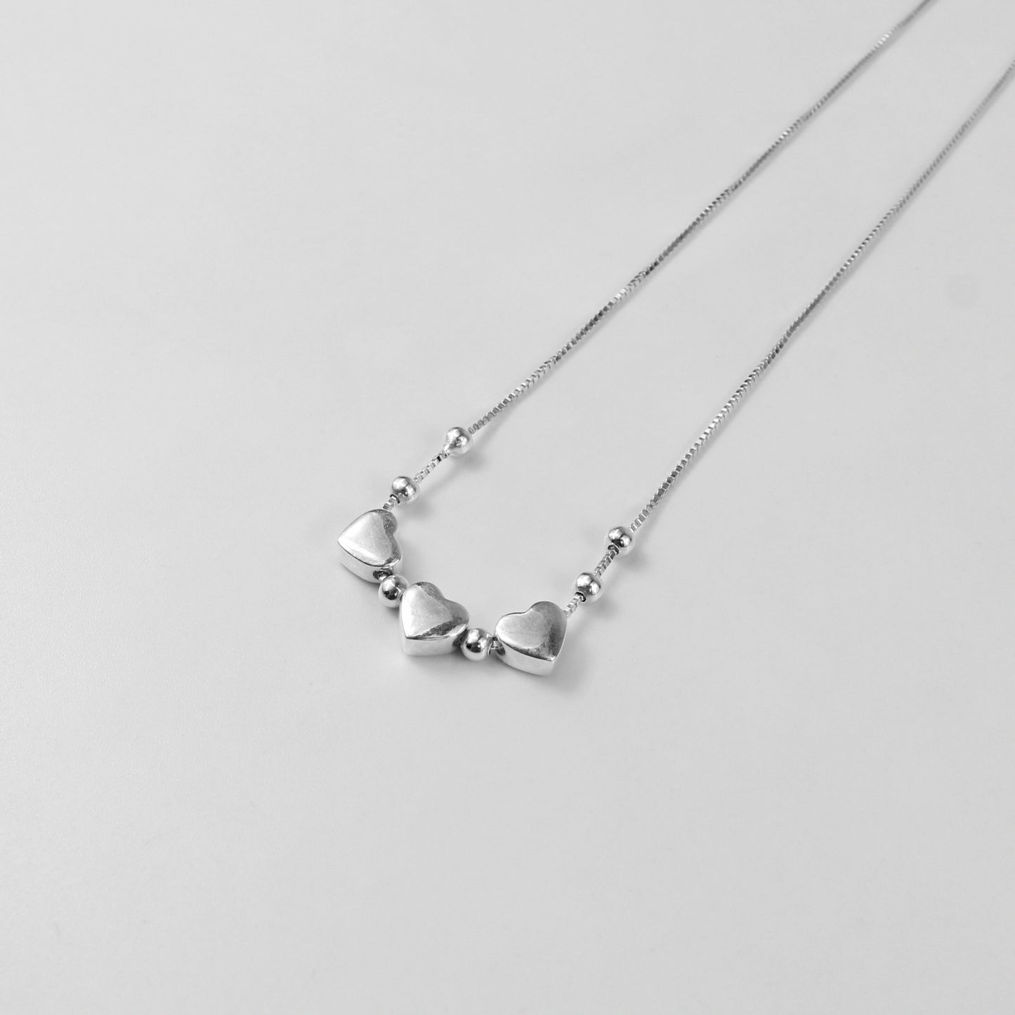 A charming necklace named 'Heartfelt Trio,' crafted from 925 sterling silver. Its design features three interlinked hearts, symbolizing love, connection, and unity with a timeless elegance.