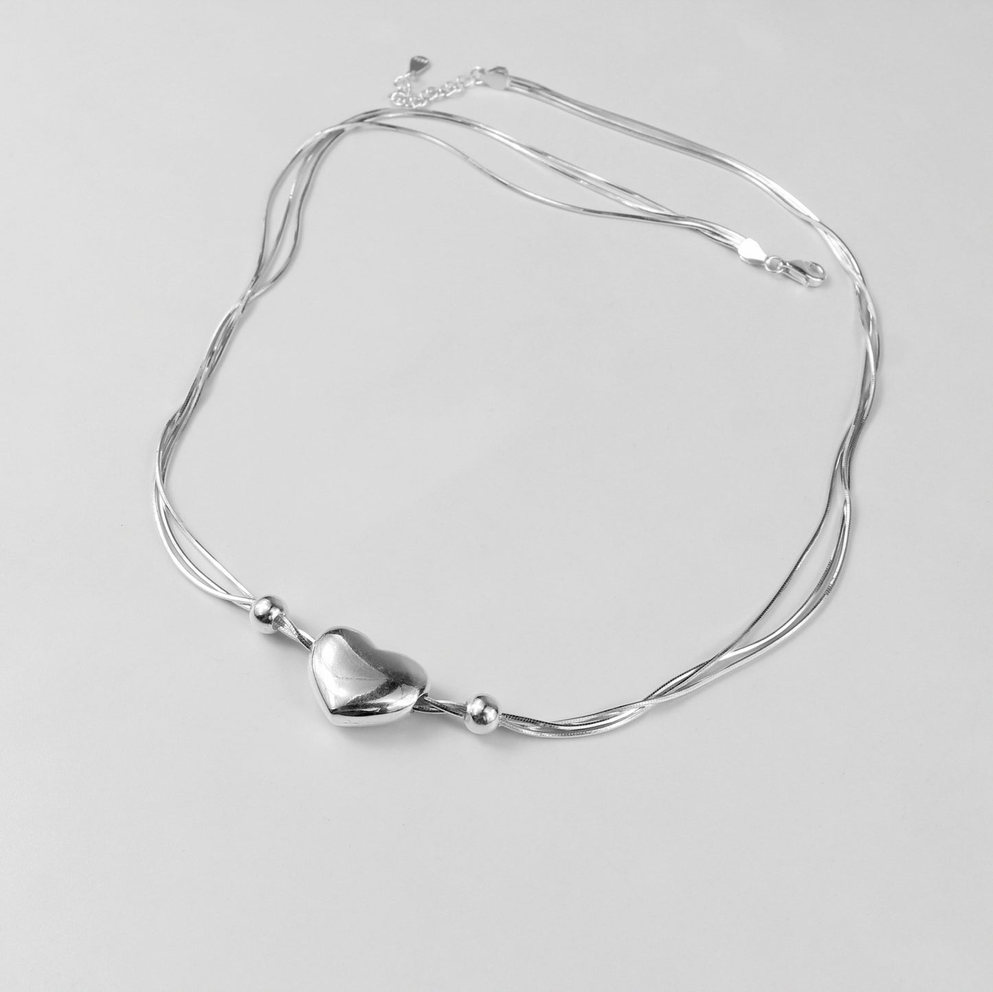 An elegant necklace named 'Heartstrings,' crafted from 925 sterling silver. Its design features delicate, intertwining strands that symbolize connection, love, and timeless beauty.