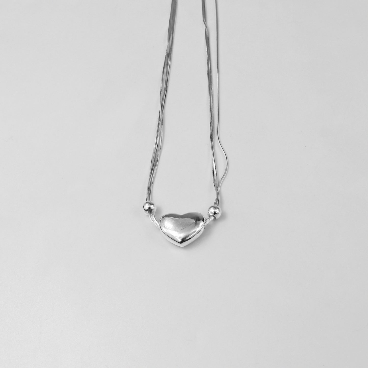 An elegant necklace named 'Heartstrings,' crafted from 925 sterling silver. Its design features delicate, intertwining strands that symbolize connection, love, and timeless beauty.