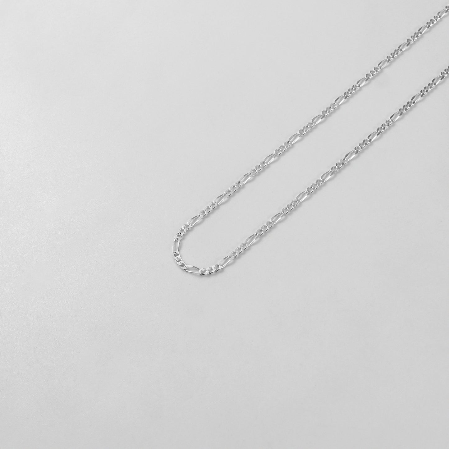 925 sterling silver necklace named 'Thin Figaro,' featuring a classic and delicate chain design with alternating short and long links. Its timeless elegance and understated sophistication make it a versatile accessory for any outfit or occasion.