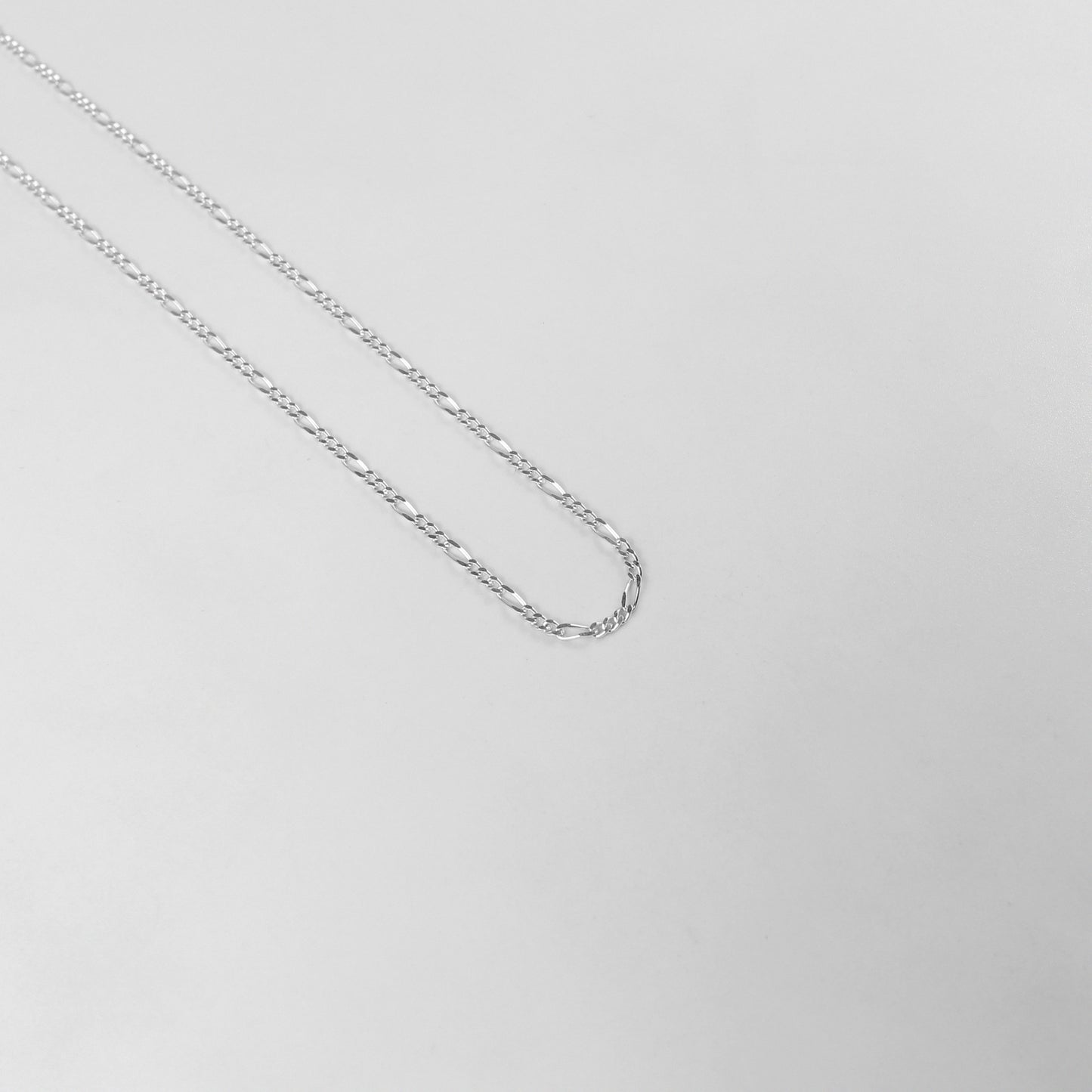 925 sterling silver necklace named 'Thin Figaro,' featuring a classic and delicate chain design with alternating short and long links. Its timeless elegance and understated sophistication make it a versatile accessory for any outfit or occasion.