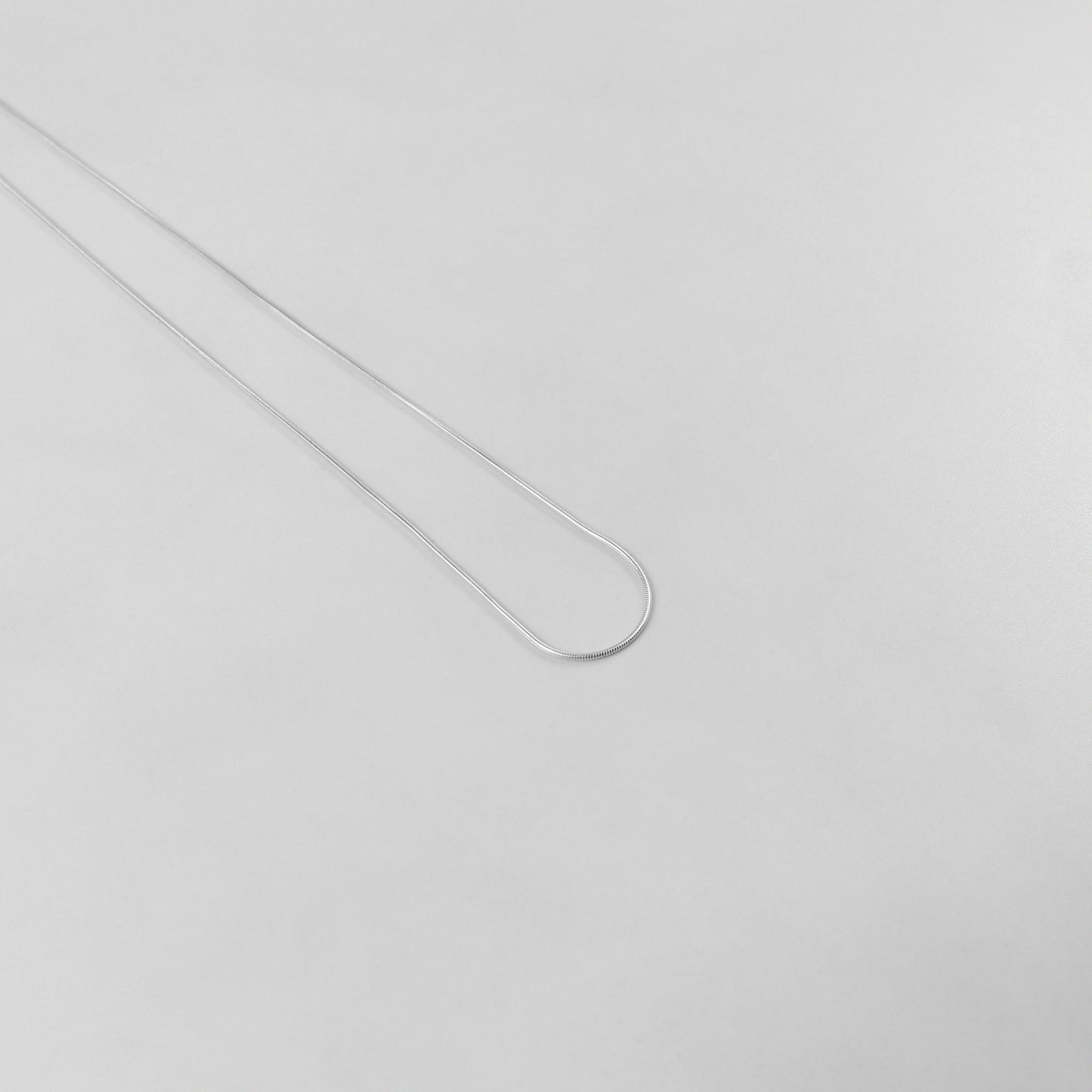 925 sterling silver necklace named 'Thin Snake,' showcasing a sleek and minimalist design with a smooth, fluid silhouette resembling the elegance of a snake's movement. Its understated sophistication makes it a versatile and timeless piece