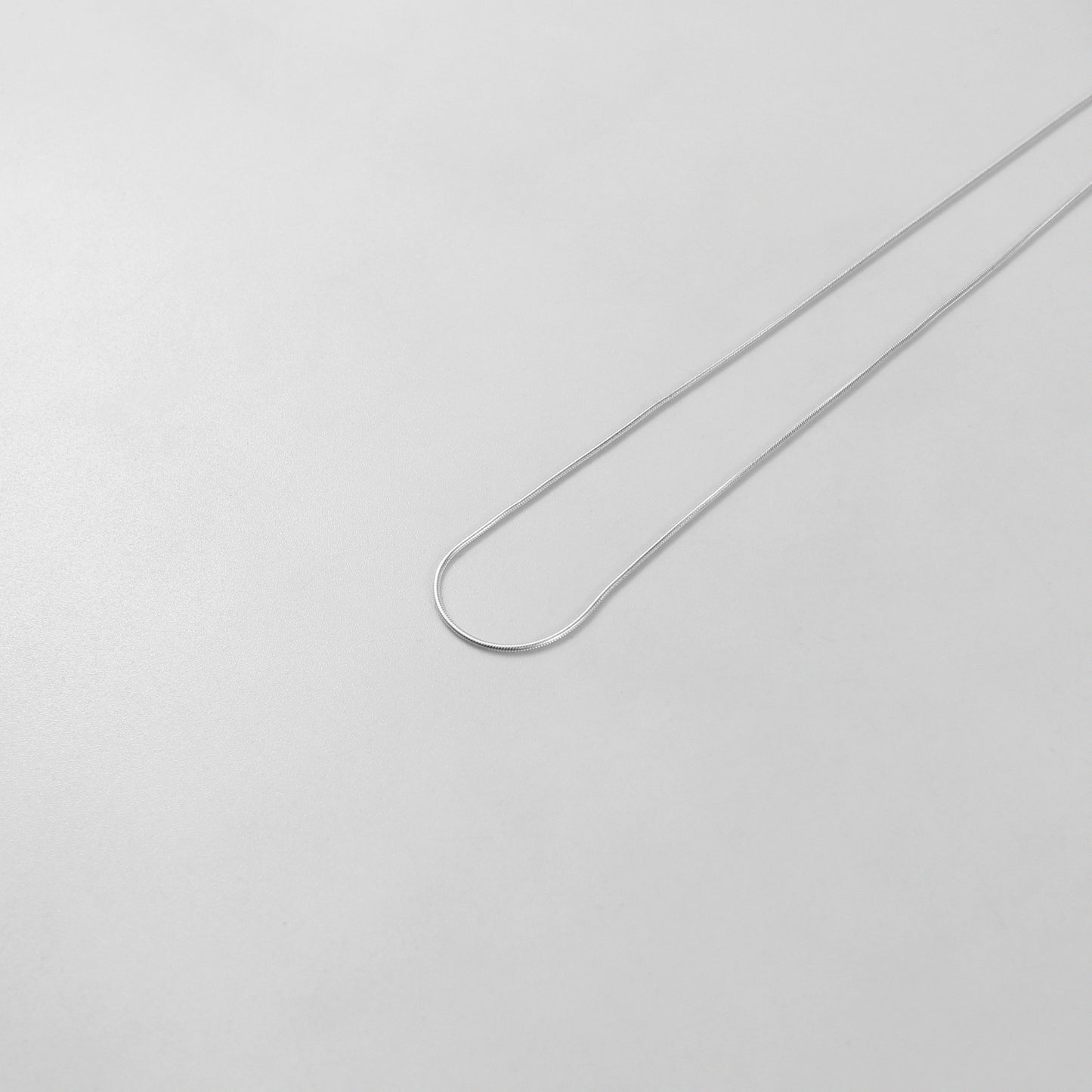 925 sterling silver necklace named 'Thin Snake,' showcasing a sleek and minimalist design with a smooth, fluid silhouette resembling the elegance of a snake's movement. Its understated sophistication makes it a versatile and timeless piece