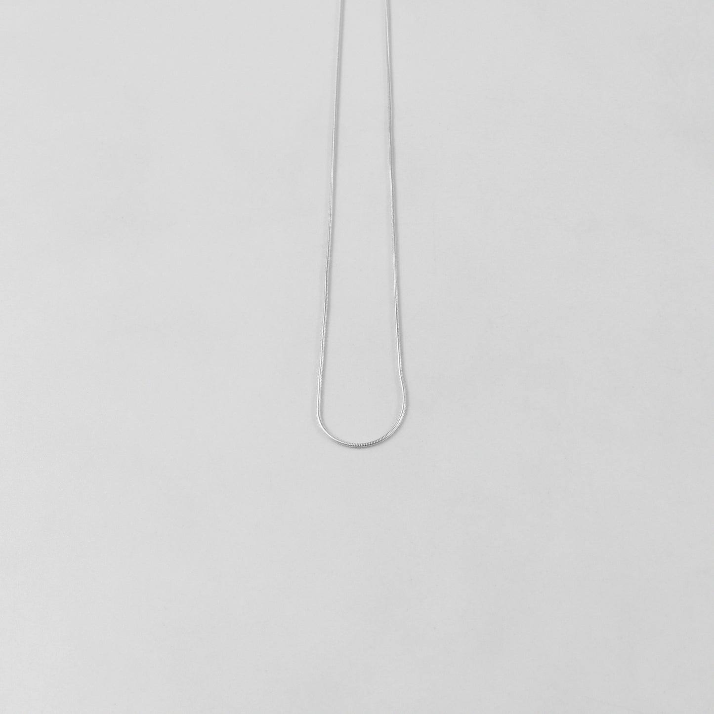 925 sterling silver necklace named 'Thin Snake,' showcasing a sleek and minimalist design with a smooth, fluid silhouette resembling the elegance of a snake's movement. Its understated sophistication makes it a versatile and timeless piece