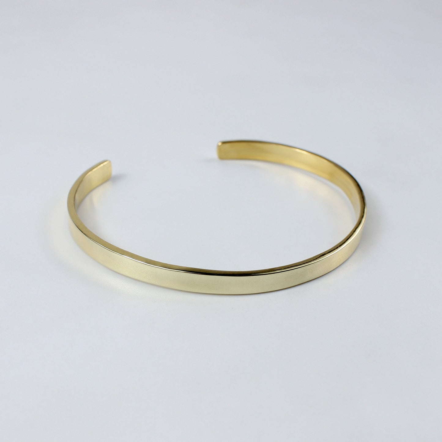 An exquisite brass cuff plated with 18k gold, designed with clean lines and a high-shine finish. This LuxeCuff Bracelet embodies modern glamour and sophistication.