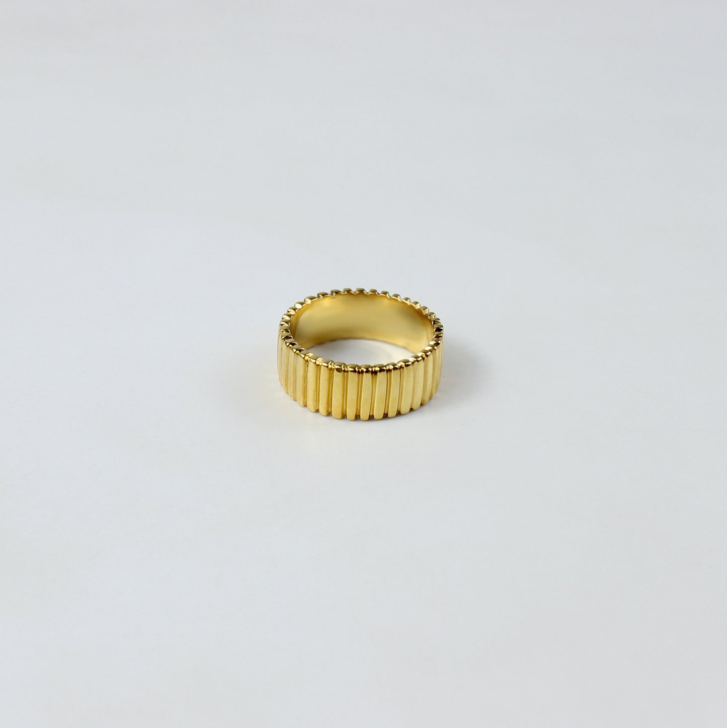 A sleek and stylish band ring crafted from brass with an 18k gold plating, featuring a refined grooved pattern. This elegant design offers a modern touch, perfect for enhancing both everyday and special occasion outfits.