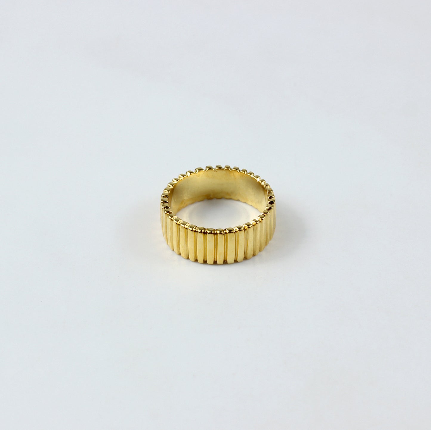 A sleek and stylish band ring crafted from brass with an 18k gold plating, featuring a refined grooved pattern. This elegant design offers a modern touch, perfect for enhancing both everyday and special occasion outfits.