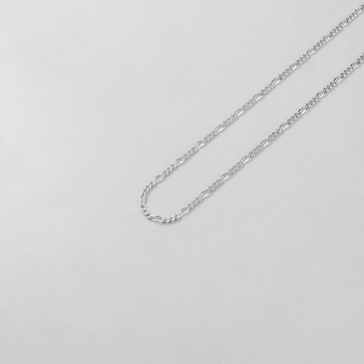 925 sterling silver necklace named 'Thin Figaro,' featuring a classic and delicate chain design with alternating short and long links. Its timeless elegance and understated sophistication make it a versatile accessory for any outfit or occasion.