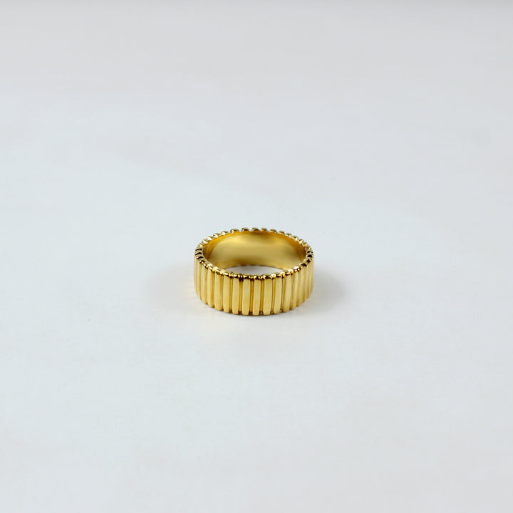A sleek and stylish band ring crafted from brass with an 18k gold plating, featuring a refined grooved pattern. This elegant design offers a modern touch, perfect for enhancing both everyday and special occasion outfits.